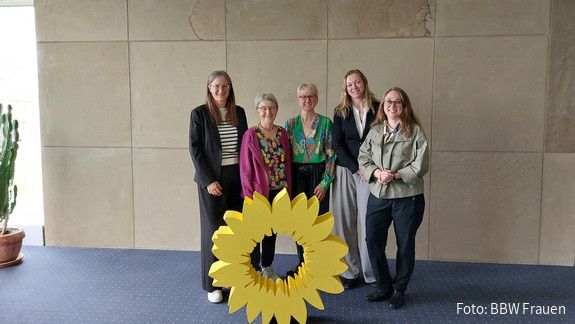 Gespräch der BBW Frauen mit MdL Stefanie Seemann Fünf Frauen stehen hinter einem gelben Aufsteller im Design einer großen gelben Blüte