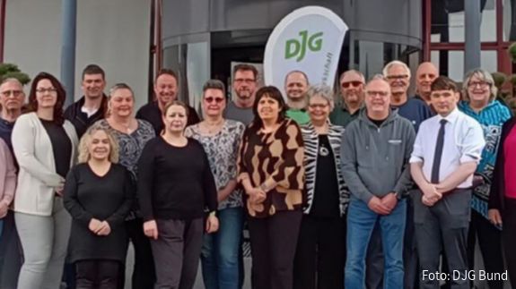 Eine Menschengruppe steht mit Blick zur Kamera vor einem Hoteleingang