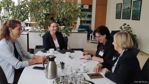 Drei Frauen sitzen an einem Tisch und diskutieren